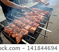 High angle shot of succulent pork shashlik kebabs grilling on metal skewers over hot coals for outdoor picnic barbecue lunch preparation 141844694