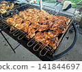 Top perspective view of delicious chicken meat roasting in double grill grate over burning charcoal embers during outdoor barbecue picnic 141844697