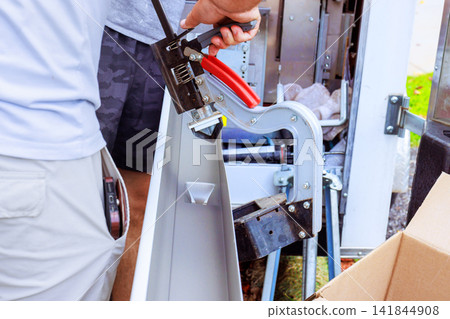 Handy man operates tool cutting hole in gutter while working on equipment at construction site 141844908