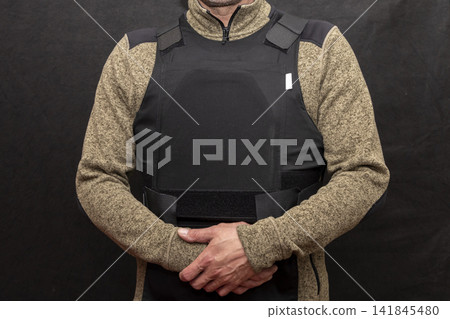 A muscular military man in a bulletproof vest on a black background. A muscular military man in a bulletproof vest on a black background. 141845480