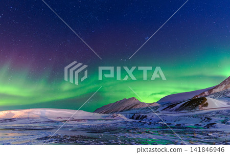 Aurora Borealis Over Snowy Arctic Mountains and Starry Night Sky Aurora Borealis Over Snowy Arctic Mountains and Starry Night Sky 141846946