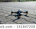 Black drone waiting on the stone road. Innovative modern technology. 141847208
