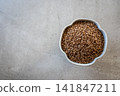 Gray bowl with uncooked roasted buckwheat on the stone table for healthy food. Cooking concept. Top view. 141847211