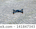 Black drone waiting on the stone road. Innovative modern technology. 141847343