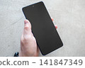 Hand of man take new mobile phone on the stone table background. Smartphone for work in office. 141847349