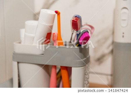 Toothbrushes and dental oral toothpastes in plastic container on shelf bathroom 141847424