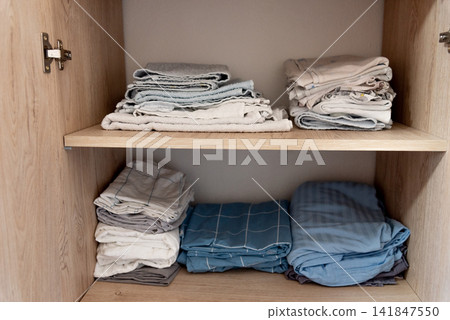 Bed linen, sheets and pillowcases and towels neatly stacked in closet in bedroom Bed linen, sheets and pillowcases and towels neatly stacked in closet in bedroom 141847550
