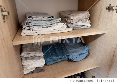 Bed linen, sheets and pillowcases and towels neatly stacked in closet in bedroom Bed linen, sheets and pillowcases and towels neatly stacked in closet in bedroom 141847551