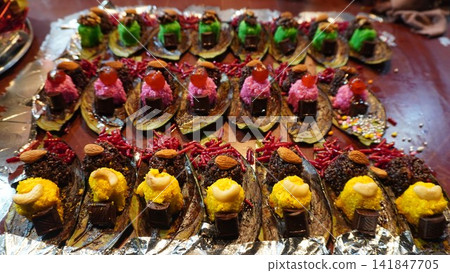 Assorted paan arranged neatly with colorful toppings on foil platter, traditional food display concept Assorted paan arranged neatly with colorful toppings on foil platter, traditional food display concept 141847705