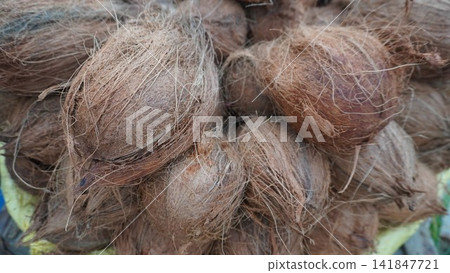 Stack of raw brown coconuts kept on display at a street food market stall, tropical fruit retail and sales business concept Stack of raw brown coconuts kept on display at a street food market stall, tropical fruit retail and sales business concept 141847721