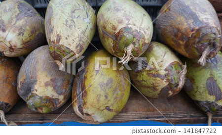 Fresh green raw coconuts piled at a local market stall, ready for sale and consumption, organic fruit and food concept Fresh green raw coconuts piled at a local market stall, ready for sale and consumption, organic fruit and food concept 141847722
