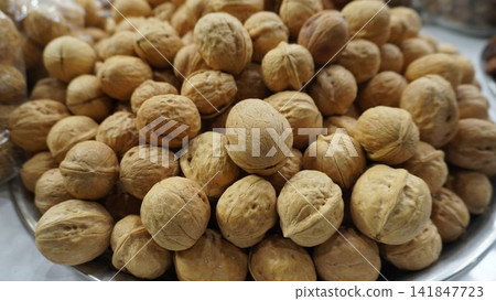 Large pile of whole walnuts kept for sale at a dry fruit shop in a busy local market, healthy snacks and nutrition concept 141847723