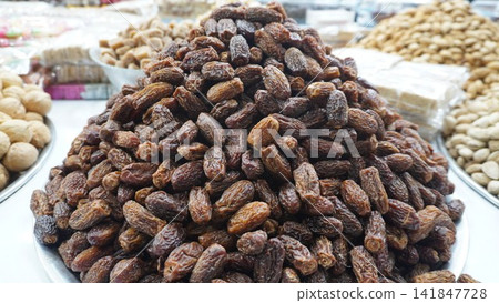 Large pile of sweet brown dates kept for sale at a street market stall, food trade and healthy commerce business concept Large pile of sweet brown dates kept for sale at a street market stall, food trade and healthy commerce business concept 141847728