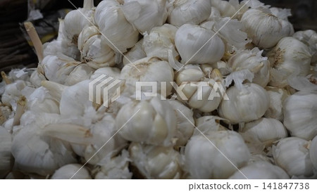 Large pile of fresh white garlic bulbs at a vegetable market stall, organic cooking ingredient and food sales concept Large pile of fresh white garlic bulbs at a vegetable market stall, organic cooking ingredient and food sales concept 141847738