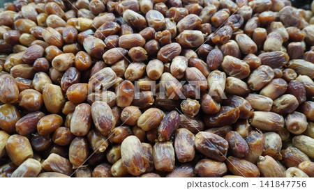 Large pile of fresh brown dates on display at a local market stall, healthy food snack commerce and retail concept Large pile of fresh brown dates on display at a local market stall, healthy food snack commerce and retail concept 141847756