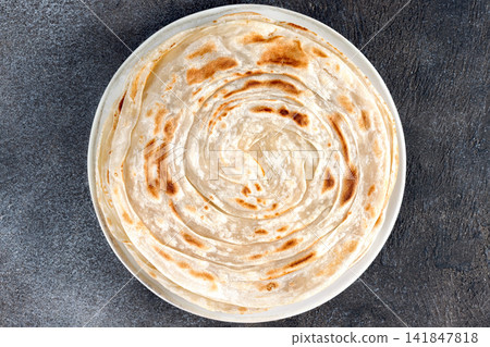 Traditional Indian paratha on gray background. Indian food. Top view. Close up Traditional Indian paratha on gray background. Indian food. Top view. Close up 141847818
