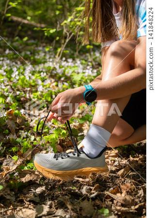 Woman tying shoelaces on running shoes during an outdoor workout Woman tying shoelaces on running shoes during an outdoor workout 141848224