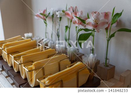 Cozy cafe counter with yellow napkins in brass holders and pink alstroemeria flowers Cozy cafe counter with yellow napkins in brass holders and pink alstroemeria flowers 141848233