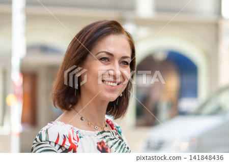 Smiling middle aged woman with bob haircut looking aside outdoors 141848436