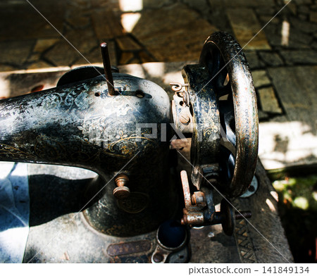 Kharkiv, Ukraine - July 15, 2021: Worn handwheel and decorated body of old Singer sewing machine Kharkiv, Ukraine - July 15, 2021: Worn handwheel and decorated body of old Singer sewing machine 141849134