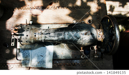Kharkiv, Ukraine - July 15, 2021: Top view of weathered Singer sewing machine on wooden table Kharkiv, Ukraine - July 15, 2021: Top view of weathered Singer sewing machine on wooden table 141849135