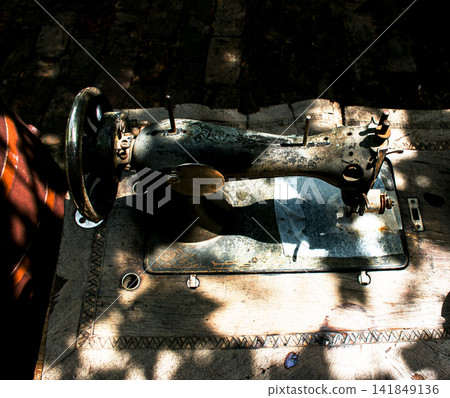 Kharkiv, Ukraine - July 15, 2021: Old Singer sewing machine photographed from above in dappled light Kharkiv, Ukraine - July 15, 2021: Old Singer sewing machine photographed from above in dappled light 141849136