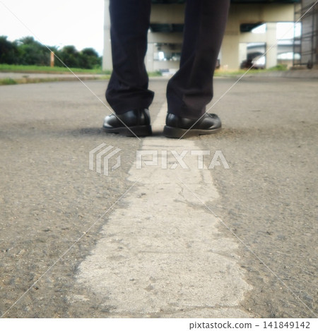A conceptual image of a businessman's feet standing on the white line of a road. A conceptual image of a businessman's feet standing on the white line of a road. 141849142