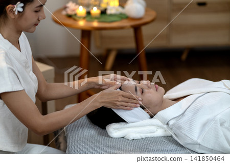 Asian spa therapist performs calming facial massage on adult woman promoting skin wellness beauty relaxation at luxurious health center Asian spa therapist performs calming facial massage on adult woman promoting skin wellness beauty relaxation at luxurious health center 141850464