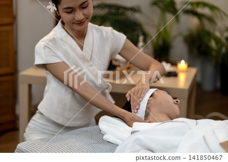 Asian adult woman spa therapist massages clients neck shoulder for relaxation wellness at peaceful serene spa environment professional care tranquil ambiance 141850467