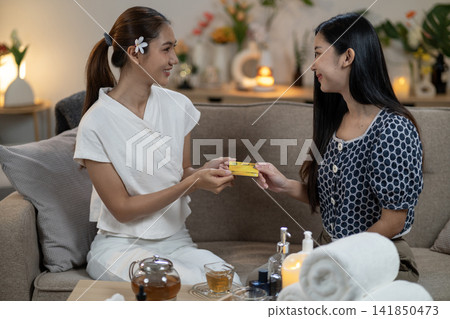 Asian women exchanging credit card payment during spa treatment relaxation wellness service at home comfortable environment Asian women exchanging credit card payment during spa treatment relaxation wellness service at home comfortable environment 141850473