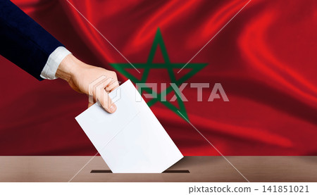 Morocco Parliamentary vote 2026. Hand placing a ballot in ballot box with the Moroccan flag in the background Morocco Parliamentary vote 2026. Hand placing a ballot in ballot box with the Moroccan flag in the background 141851021