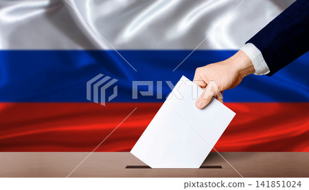Russia Parliamentary vote 2026. Hand placing a ballot in ballot box with the Russian flag in the background Russia Parliamentary vote 2026. Hand placing a ballot in ballot box with the Russian flag in the background 141851024