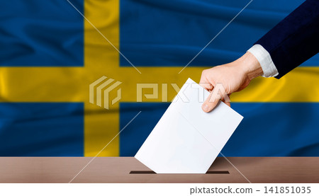 Sweden Parliamentary vote 2026. Hand placing a ballot in ballot box with the Swedish flag in the background Sweden Parliamentary vote 2026. Hand placing a ballot in ballot box with the Swedish flag in the background 141851035