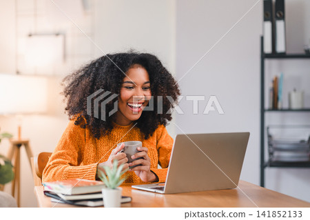 Smiling African American woman using a laptop while working from home. 141852133