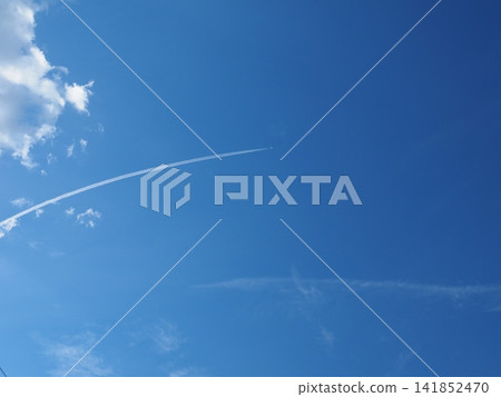 一條白色的尾跡平緩地橫跨盛夏湛藍的天空。廣闊的藍天與飛機尾跡。 一條白色的尾跡平緩地橫跨盛夏湛藍的天空。廣闊的藍天與飛機尾跡。 141852470