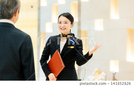 A female concierge serving a male customer. A female concierge serving a male customer. 141852826