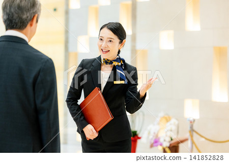 A female concierge serving a male customer. A female concierge serving a male customer. 141852828