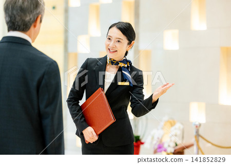 一位女禮賓員正在為一位男性顧客服務。 一位女禮賓員正在為一位男性顧客服務。 141852829