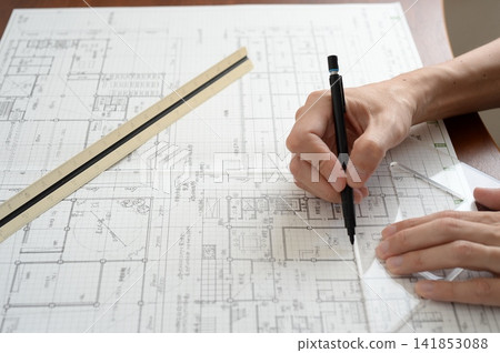 建築師用尺和鋼筆在建築圖上畫線。 建築師用尺和鋼筆在建築圖上畫線。 141853088