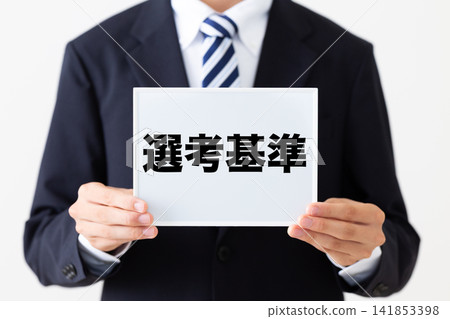 A young male businessman in a business suit holding a whiteboard with selection criteria. A young male businessman in a business suit holding a whiteboard with selection criteria. 141853398