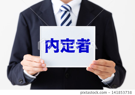 A young businessman in a business suit holding a whiteboard of job offer recipients. A young businessman in a business suit holding a whiteboard of job offer recipients. 141853738