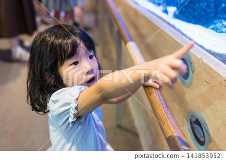A young Japanese girl points at an aquarium tank. A young Japanese girl points at an aquarium tank. 141853952