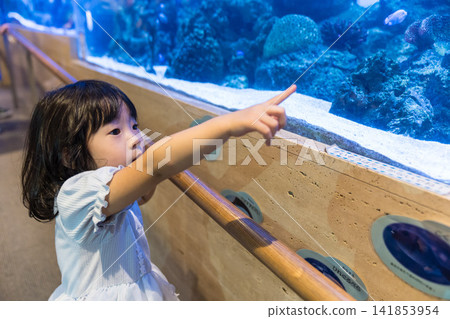 一位日本小女孩指著一個水族箱。 141853954