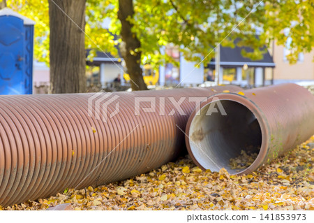 Pipes lay on ground covered with yellow leaves in autumn season Pipes lay on ground covered with yellow leaves in autumn season 141853973