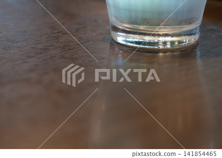 A glass of water reflected on a wooden table A glass of water reflected on a wooden table 141854465