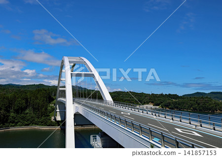 The magnificent Kesennuma Oshima Bridge shines brightly in the clear blue sky. The magnificent Kesennuma Oshima Bridge shines brightly in the clear blue sky. 141857153