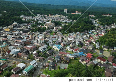 一張空拍照片,展現了群馬縣草津町的居民區和山脈。 一張空拍照片,展現了群馬縣草津町的居民區和山脈。 141857451