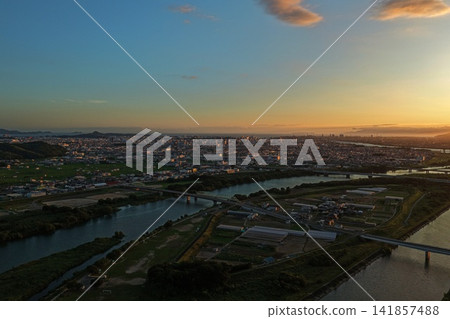 An aerial photograph of a summer sunset over Wakayama City, capturing the Kinokawa River and the city's urban area. An aerial photograph of a summer sunset over Wakayama City, capturing the Kinokawa River and the city's urban area. 141857488