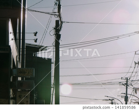 夕陽西下,街角電線桿和電線交會處,在燈光映襯下勾勒出剪影。 夕陽西下,街角電線桿和電線交會處,在燈光映襯下勾勒出剪影。 141859586