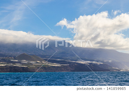 Scenic view from the sea of the dark volcanic lava delta formed by Tajogaite eruption, with banana plantations on the cliffs in La Palma, Canary Islands, Spain Scenic view from the sea of the dark volcanic lava delta formed by Tajogaite eruption, with banana plantations on the cliffs in La Palma, Canary Islands, Spain 141859985